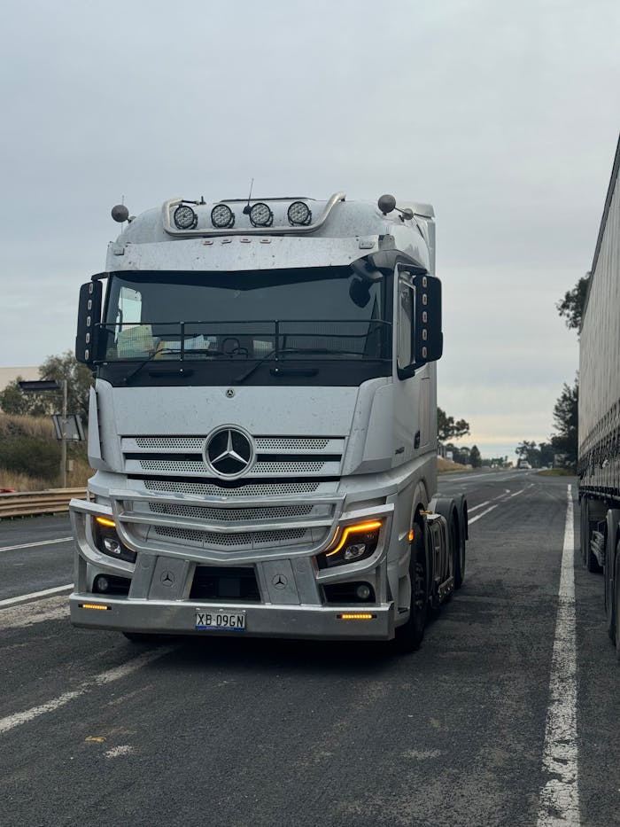 A sleek white truck travels along a highway, showcasing modern transportation.